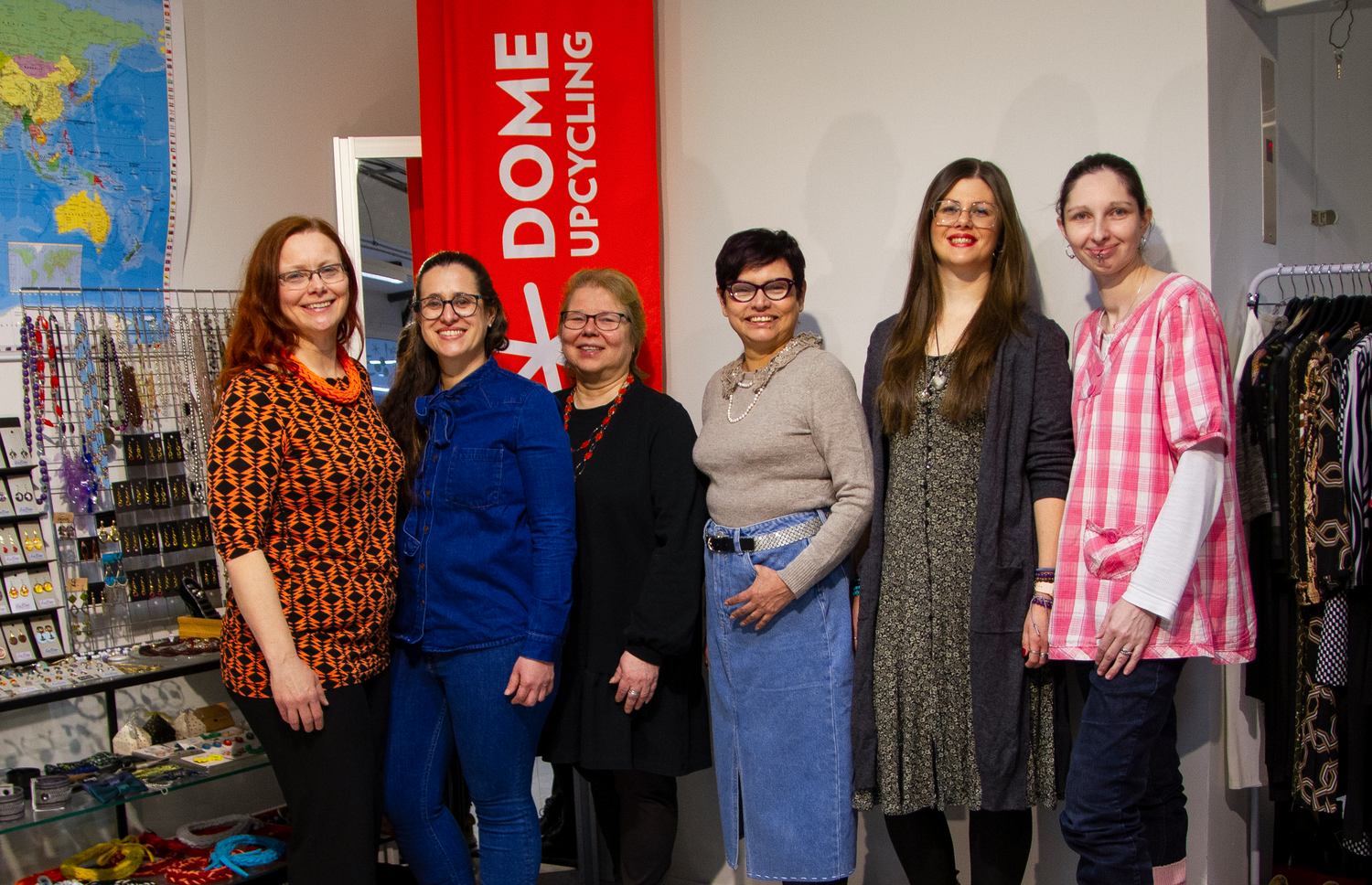 Group of women posing in a store with 'Dome Upcycling' sign in the background
